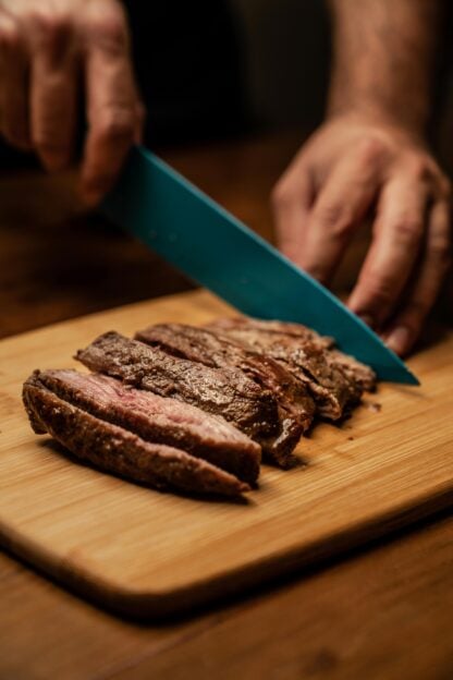 Denver steak being sliced on a cutting board.