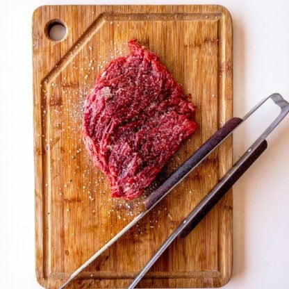 Uncooked flank steak on a cutting board.